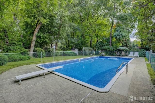 view of pool featuring a diving board, fence, and a patio