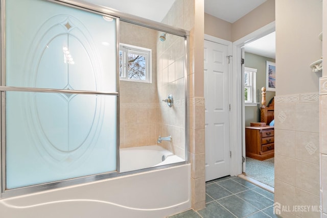 full bath featuring combined bath / shower with glass door, healthy amount of natural light, tile patterned flooring, and ensuite bathroom