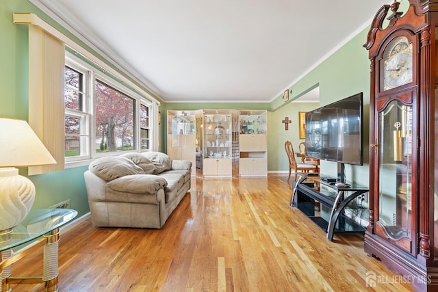 living room with light wood finished floors, ornamental molding, and baseboards