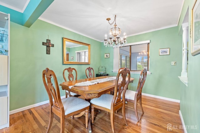 dining room with light wood finished floors, a chandelier, baseboards, and ornamental molding