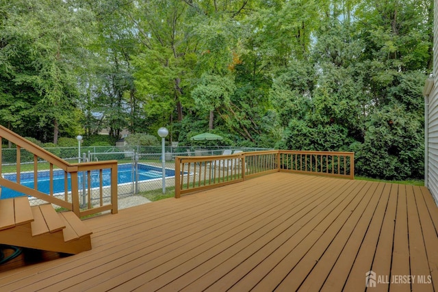wooden terrace featuring a fenced backyard and view of wooded area