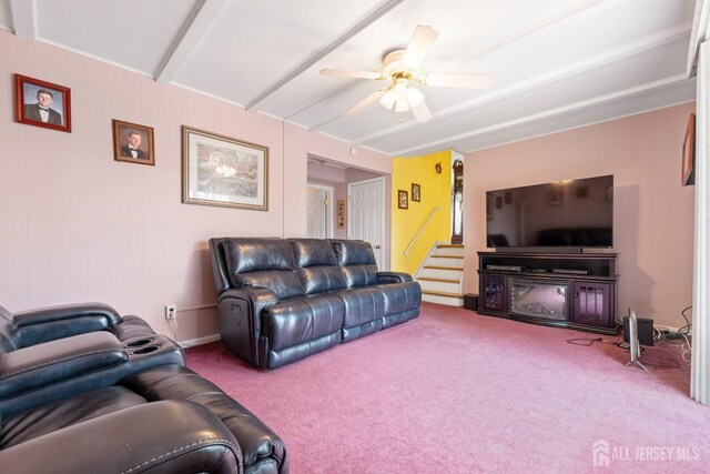 carpeted living area featuring a ceiling fan, stairs, and beam ceiling