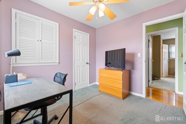 home office featuring carpet floors, ceiling fan, and baseboards