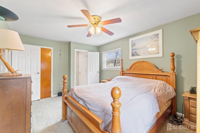 bedroom featuring light colored carpet, baseboards, and a ceiling fan