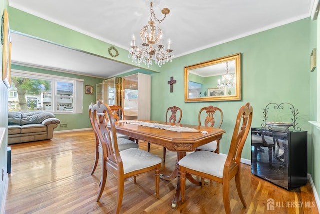 dining room featuring a chandelier, crown molding, wood finished floors, and baseboards