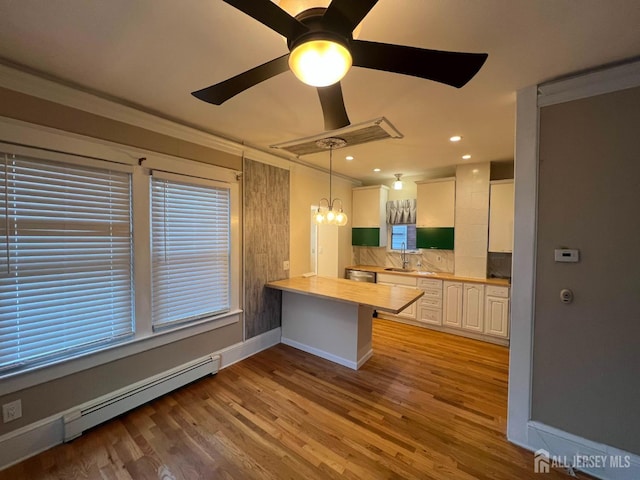 kitchen featuring kitchen peninsula, pendant lighting, a baseboard radiator, light hardwood / wood-style flooring, and white cabinetry