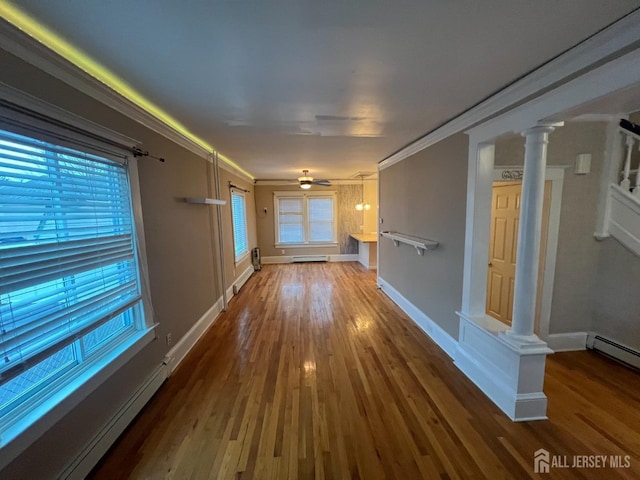 hall featuring baseboard heating, a healthy amount of sunlight, wood-type flooring, and ornamental molding