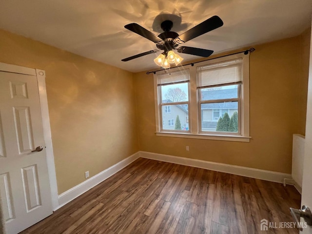 spare room featuring ceiling fan, dark hardwood / wood-style flooring, and radiator heating unit