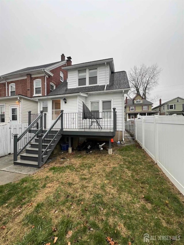 back of house featuring a wooden deck and a lawn