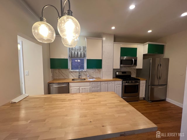 kitchen featuring wood counters, backsplash, white cabinets, appliances with stainless steel finishes, and decorative light fixtures