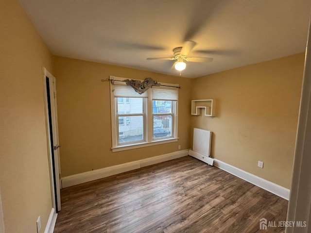 unfurnished room with ceiling fan, radiator heating unit, and dark wood-type flooring