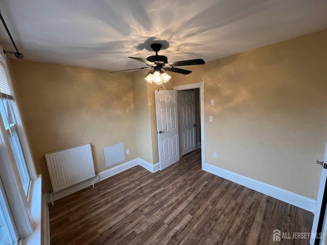 spare room featuring radiator, ceiling fan, and dark wood-type flooring