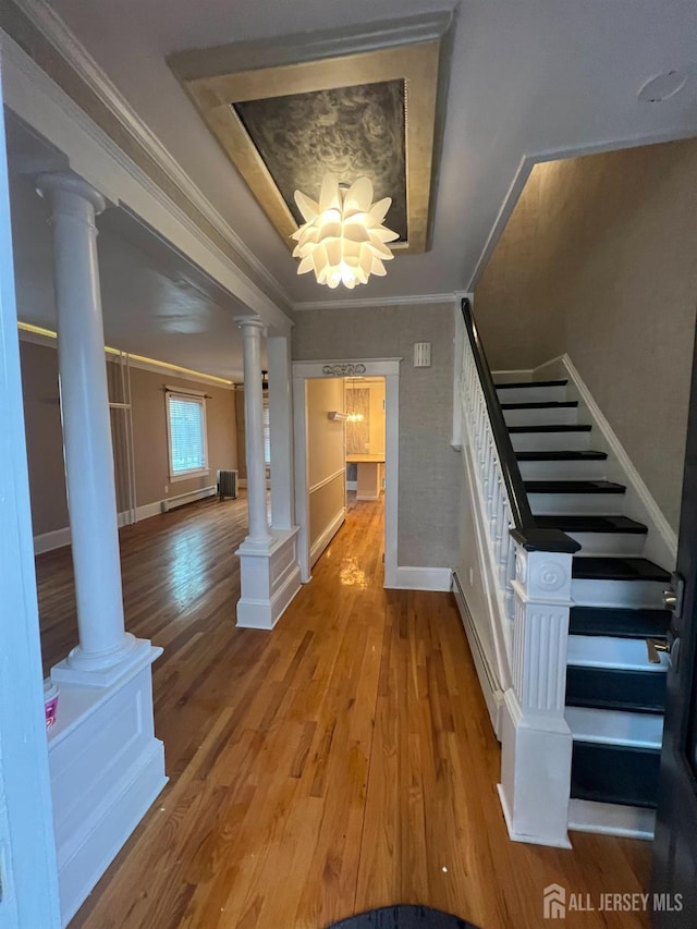 staircase featuring wood-type flooring, a raised ceiling, and ornamental molding