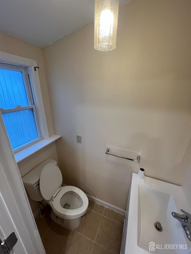 bathroom with toilet, tile patterned flooring, and sink