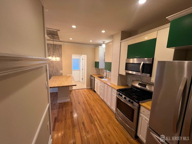 kitchen with pendant lighting, wooden counters, white cabinets, sink, and stainless steel appliances