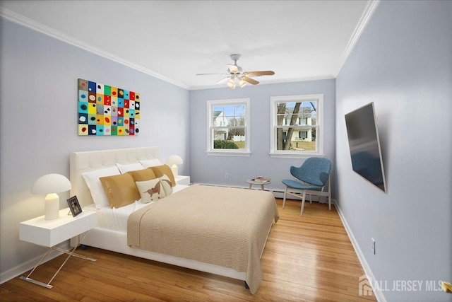 bedroom with a ceiling fan, crown molding, baseboards, and wood finished floors