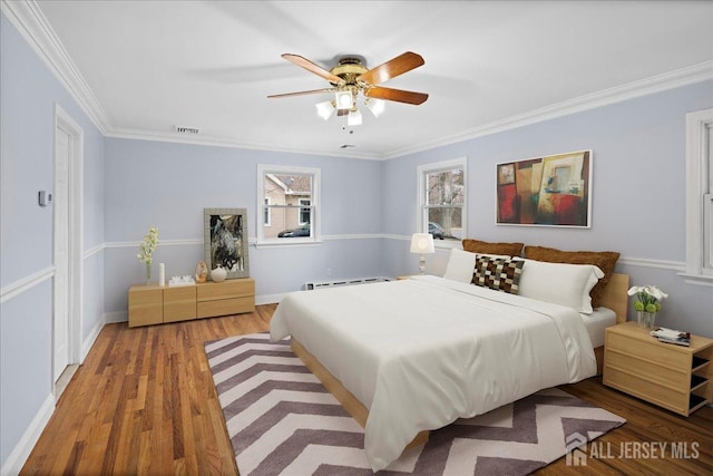 bedroom with baseboards, ceiling fan, ornamental molding, light wood-type flooring, and a baseboard heating unit