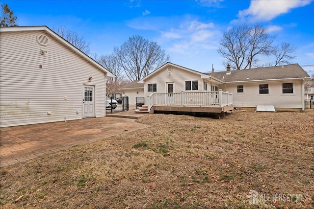 rear view of house featuring a patio, a deck, and a lawn