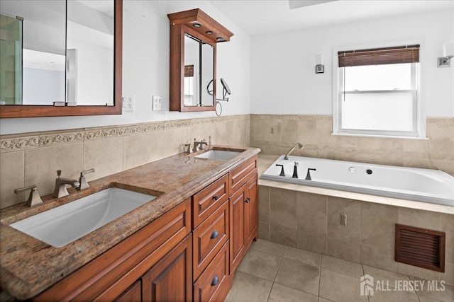 bathroom with tile patterned flooring, visible vents, a sink, and a garden tub