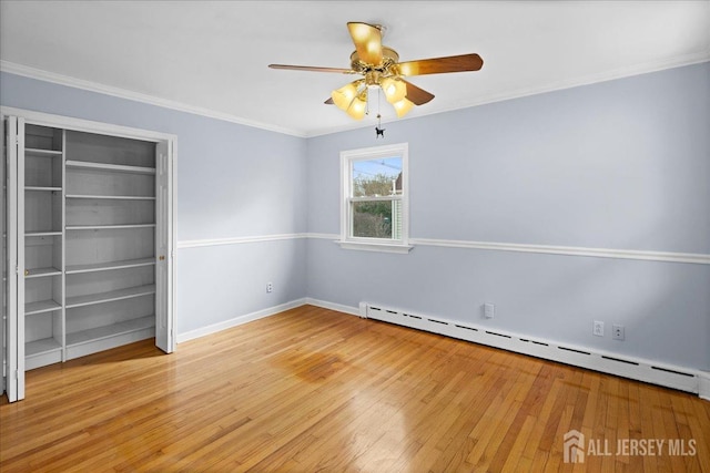 unfurnished room featuring light wood finished floors, a ceiling fan, baseboard heating, and crown molding