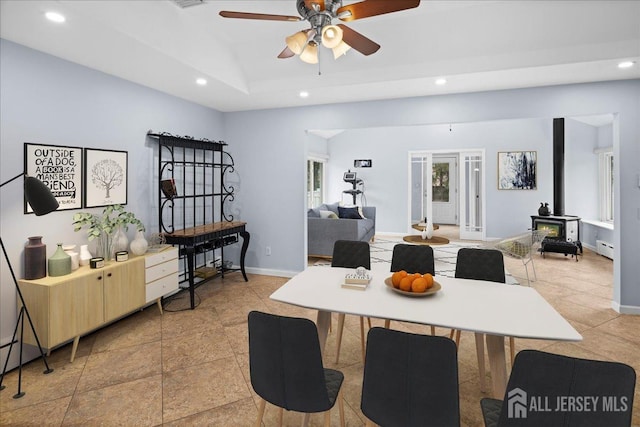 dining room with recessed lighting, a wood stove, baseboard heating, and baseboards