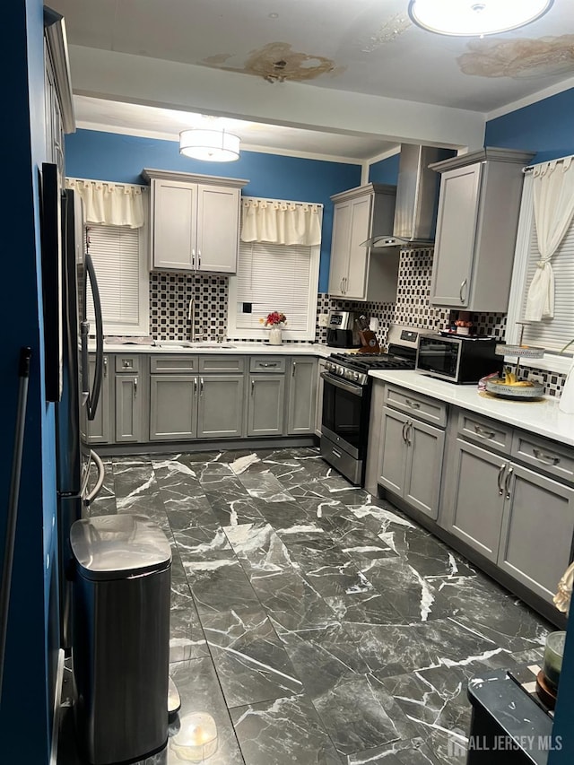 kitchen with gas stove, gray cabinets, tasteful backsplash, and wall chimney range hood