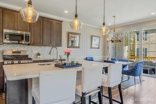 58 Begonia Ln, Monroe, NJ 08831 - kitchen with stainless steel appliances, a sink, ornamental molding, an island with sink, and decorative light fixtures