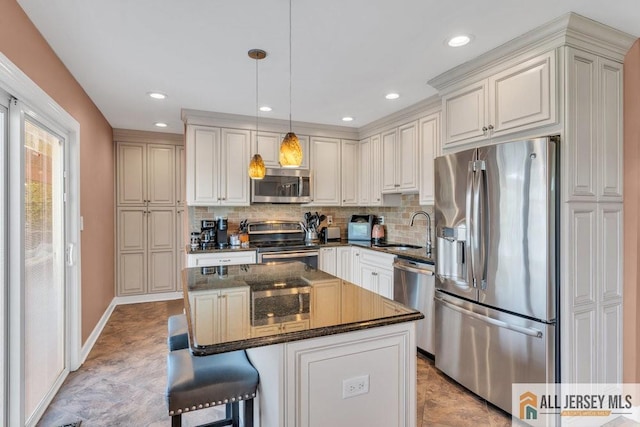 kitchen featuring decorative light fixtures, appliances with stainless steel finishes, tasteful backsplash, a center island, and a sink