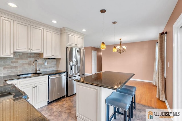 kitchen with appliances with stainless steel finishes, a sink, a chandelier, backsplash, and a kitchen island