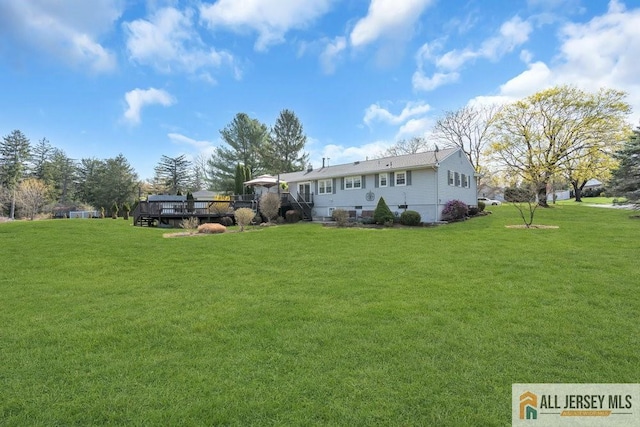 rear view of property featuring a lawn and a wooden deck