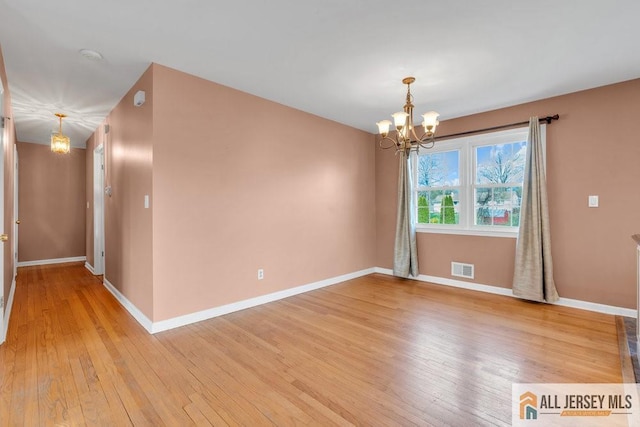 unfurnished room featuring baseboards, a chandelier, light wood-style flooring, and visible vents