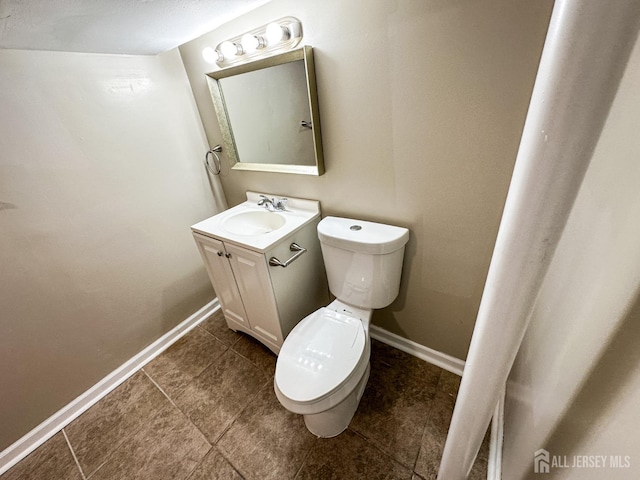 bathroom with baseboards, vanity, and toilet