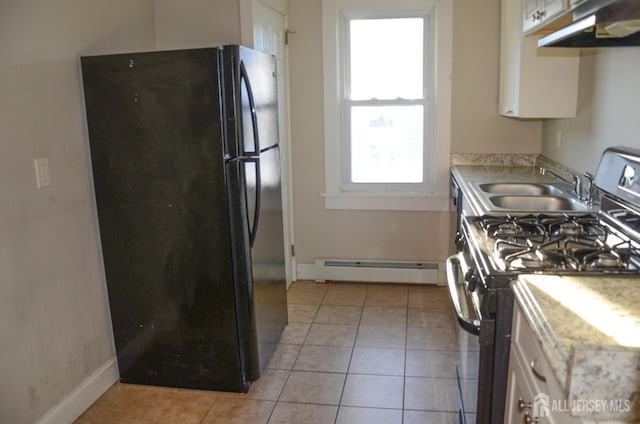 kitchen featuring stainless steel range with gas cooktop, a baseboard heating unit, freestanding refrigerator, a sink, and under cabinet range hood