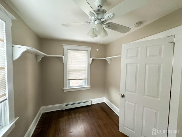 interior space featuring a baseboard heating unit, dark wood-type flooring, a ceiling fan, and baseboards