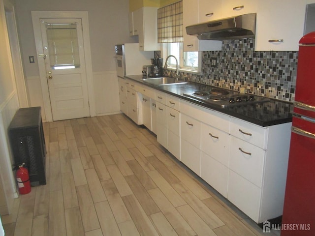 458 S Barclay St, Perth Amboy, NJ 08861 - kitchen with under cabinet range hood, stainless steel cooktop, dark countertops, white cabinets, and light wood-style floors