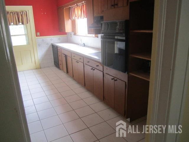458 S Barclay St, Perth Amboy, NJ 08861 - kitchen with black oven, wainscoting, light tile patterned floors, light countertops, and tile walls