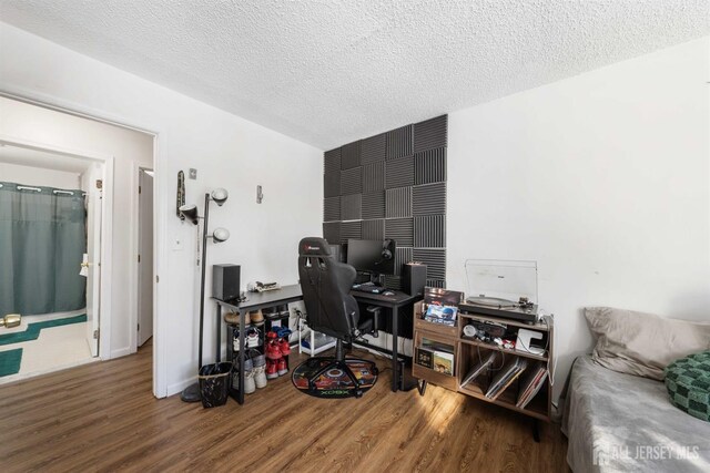 office area featuring a textured ceiling, baseboards, and wood finished floors