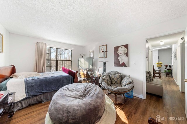 bedroom featuring a textured ceiling, baseboards, and dark wood-type flooring