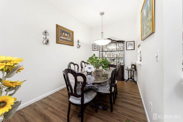 dining area featuring dark wood-type flooring and baseboards