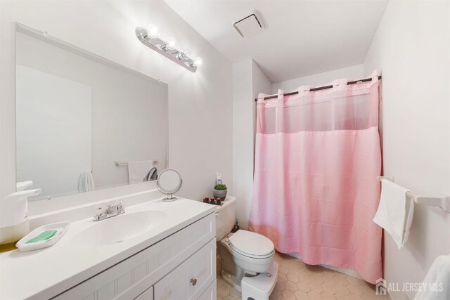 bathroom with toilet, visible vents, vanity, and tile patterned floors