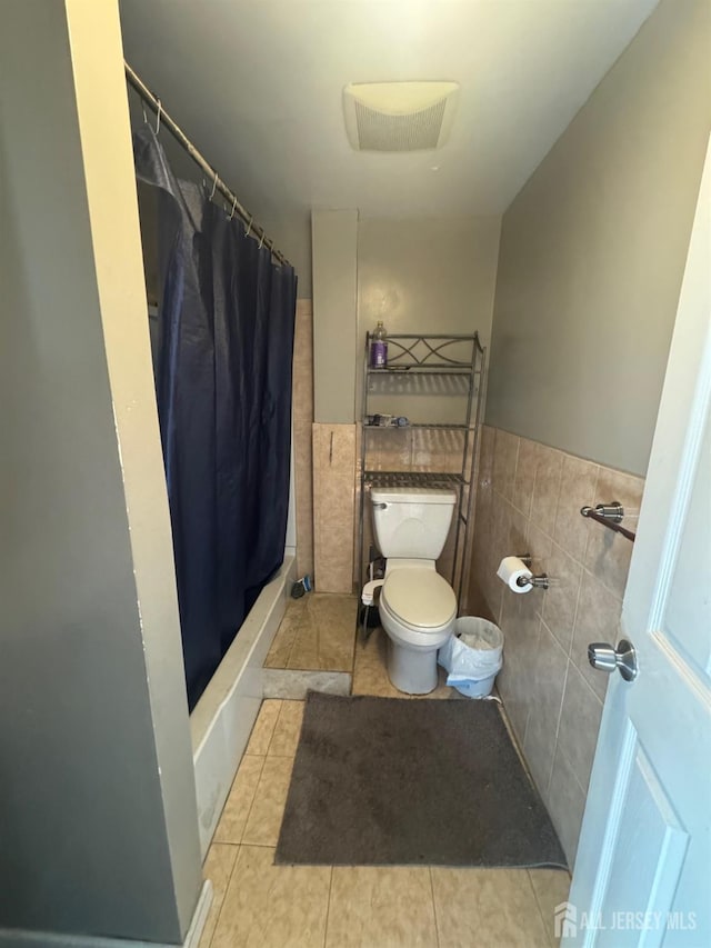 bathroom featuring tile patterned floors, toilet, tile walls, and walk in shower