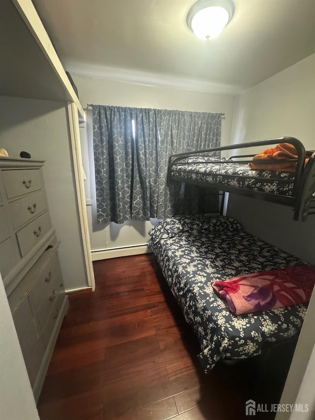 bedroom featuring dark hardwood / wood-style flooring and a baseboard heating unit