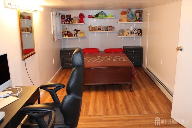 bedroom with hardwood / wood-style floors and a baseboard heating unit