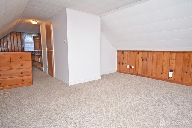 additional living space featuring lofted ceiling, carpet floors, wood walls, and baseboards