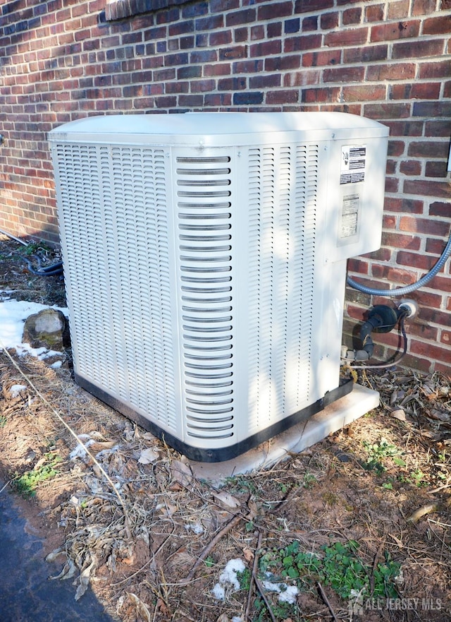 exterior details featuring cooling unit and brick siding