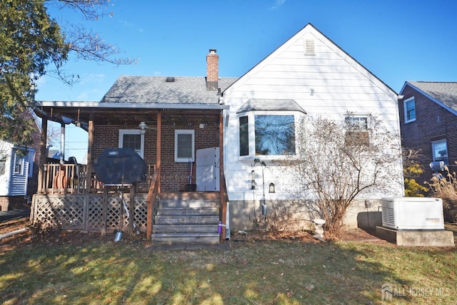 rear view of property with a chimney, roof with shingles, a deck, a yard, and brick siding