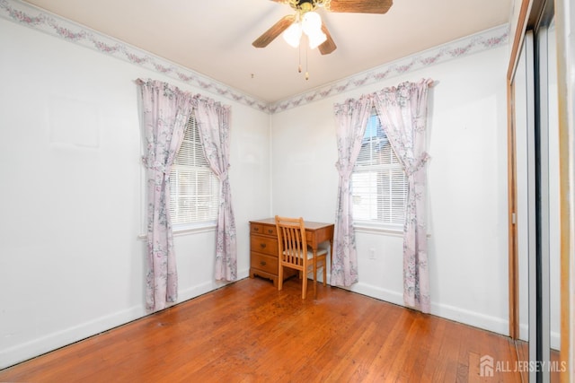 unfurnished office with a ceiling fan, baseboards, and wood finished floors