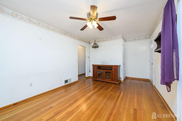 unfurnished room with arched walkways, a ceiling fan, visible vents, baseboards, and light wood-type flooring