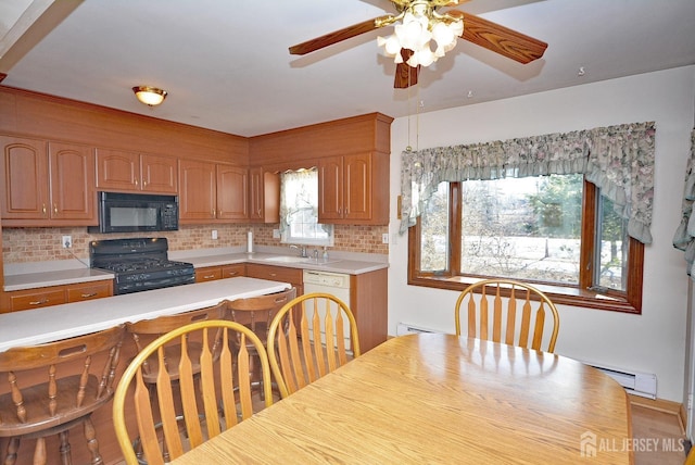 kitchen with tasteful backsplash, a baseboard radiator, light countertops, black appliances, and a sink