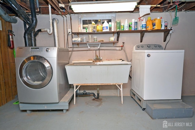 washroom featuring laundry area, washing machine and dryer, and a sink